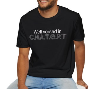 May include: A black t-shirt with the text "Well versed in C.H.A.T.G.P.T." printed in white.