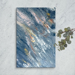 Op de afbeelding: Abstract canvas kunst met een vloeiend verfontwerp. Het kunstwerk toont een mix van blauwe, witte, gele en oranje tinten, waardoor een dynamisch en gestructureerd visueel effect ontstaat. Het canvas is rechthoekig en gemonteerd op een houten frame.