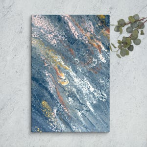 Op de afbeelding: Abstract canvas kunst met een vloeiend ontwerp. Het kunstwerk toont een mix van kleuren, waaronder tinten blauw, wit, geel en oranje. Het canvas is opgespannen en klaar om op te hangen, en biedt een moderne esthetiek voor de interieurdecoratie.