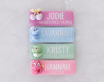 May include: Four colorful name badges with cartoon embellishments. The badges are pink, blue, and green, with names and titles printed in white. The top badge says "Jodie, Registered Nurse." The other badges say "Savannah, Assistant Nurse," "Kristy, Clinical Midwife," and "Hannah, Doctor."