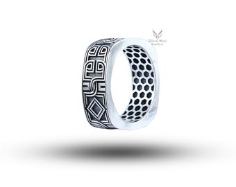 May include: A silver ring with a square design. The ring features an engraved geometric pattern on the outer surface and a honeycomb pattern on the inner surface. The ring is displayed against a white background.