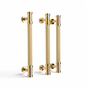 May include: Two vertical door handles with a polished gold finish. Each handle features a long, cylindrical, fluted central bar supported by two circular mounting brackets at the top and bottom, creating a clean and structured hardware design.