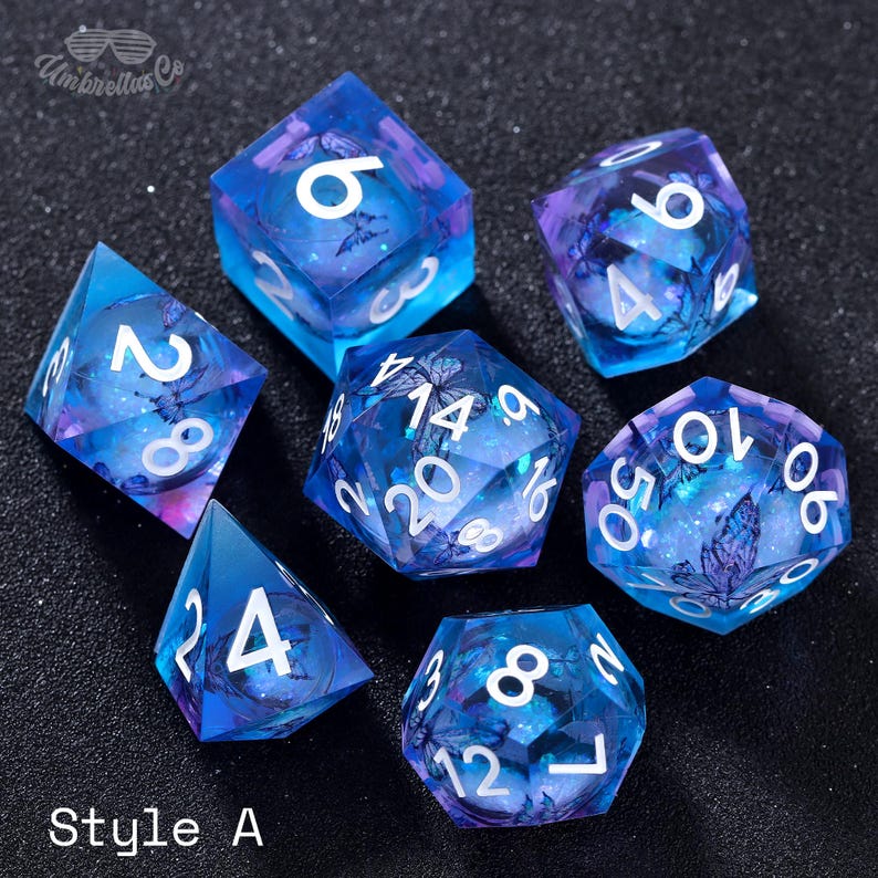 May include: Set of six blue and purple dice with white numbers and butterfly designs. The dice are numbered 2, 4, 6, 8, 10, and 14.