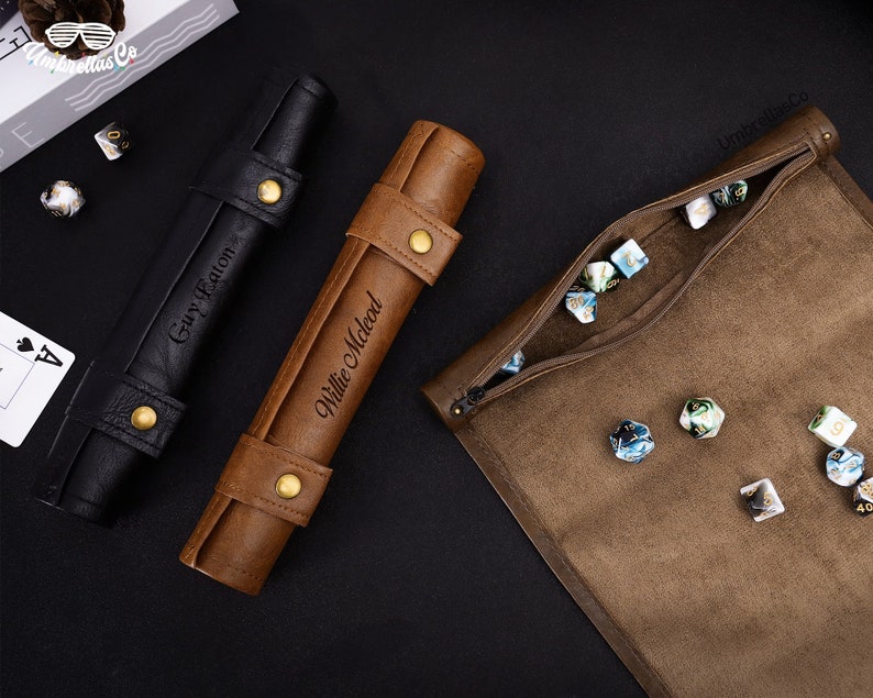 May include: Two brown leather dice rolling trays with personalized names, "Willie McLeod" and "Gary Eaton", and a brown leather dice bag with a zipper closure. The bag is filled with blue and white dice.