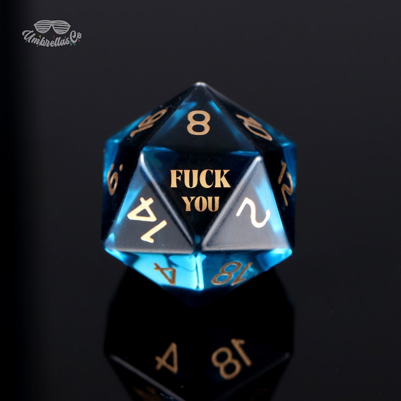 May include: A blue, 12-sided dice with gold numbers and the phrase "FUCK YOU" on one side.