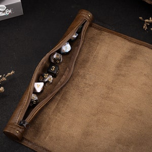 May include: A brown leather dice bag with a zipper closure. The bag is open and filled with various colored dice. The bag has the text "UmbrellasCo" printed on it.