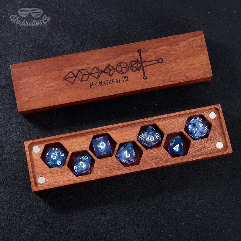May include: A wooden box with a lid, containing a set of seven iridescent dice with white numbers. The box is engraved with the text "MY NATURAL 20" and a sword design.
