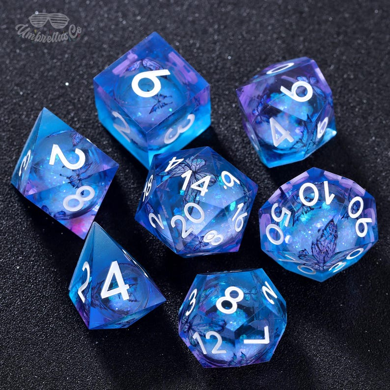 May include: Set of seven blue and purple dice with white numbers and butterfly designs. The dice are made of clear plastic with a glittery finish.