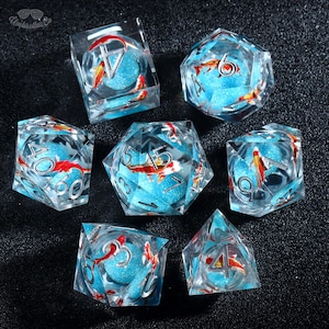 May include: A set of seven polyhedral dice with a clear resin exterior. Each die features a blue glitter interior with red and white koi fish and silver numbering. The dice are designed for tabletop gaming.