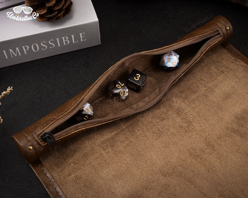 May include: A brown leather dice bag with a zipper closure. The bag is open and several dice are visible inside. The dice are black and white with gold numbers.