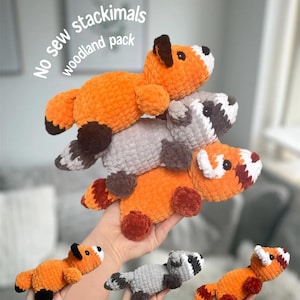 May include: A stack of four plush woodland animal toys: a fox, a raccoon, and two foxes. The toys are orange, gray, and white, with brown and black accents. The text "No sew stackimals woodland pack" is in the upper left corner.