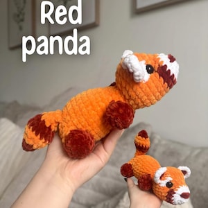 May include: Two crocheted red panda plush toys. The larger panda is held in the air, while a smaller one rests in the hand below. The pandas are orange with brown and white accents. The text "Red panda" is in the upper left corner.