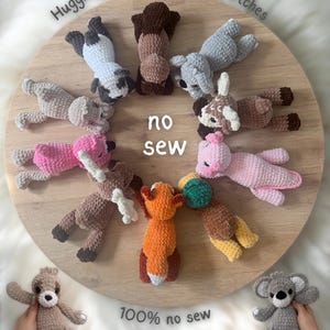 May include: A collection of crocheted animal plushies, including a raccoon, koala, fox, and bear, arranged on a wooden surface. The text "Huggie buddies 2 by lilbeanstitches", "no sew", and "100% no sew" are visible.