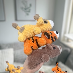 May include: A collection of handmade crochet animal toys, including a yellow dog with brown spots, an orange tiger with black stripes, and a brown bear. The toys are soft and plush, perfect for children.