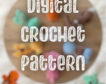 May include: A digital crochet pattern featuring the text "Digital CROCHET pattern" in white, overlaid on a blurred circular wooden surface with several small, colourful, crocheted plush figures arranged in a circular formation around the centre.