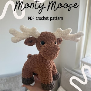 May include: A crocheted brown moose toy with white antlers and black eyes. The text "Monty Moose" and "PDF crochet pattern" are displayed in the background. The moose is a handmade item.
