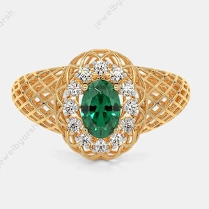 May include: A gold ring featuring an oval-cut green gemstone at the center, surrounded by a halo of small round white stones. The ring band and the setting around the center stones display an intricate, openwork lattice or grid design.