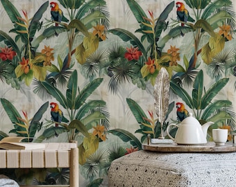 Puede incluir: Un papel tapiz tropical con un patrón repetitivo de hojas verdes de palmera, flores rojas y amarillas y loros coloridos. El papel tapiz se muestra en una habitación con un banco de madera, un otomano estampado y una tetera blanca.