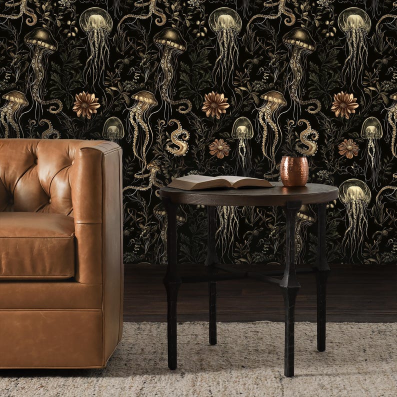 May include: A black and gold wallpaper with a repeating pattern of jellyfish and octopus tentacles. The wallpaper is displayed on a wall behind a brown leather sofa and a black metal side table with a book on top.
