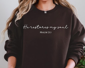 May include: A black sweatshirt with the text "He restores my soul" and "PSALM 23:3" in white lettering.