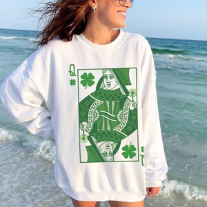 May include: White sweatshirt with a green Queen of Hearts playing card graphic. The card features a green shamrock design and the letter Q.