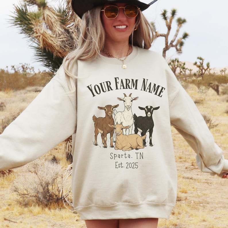 May include: Cream-colored sweatshirt with a goat graphic and the text "Your Farm Name." The graphic features four goats in various poses. Below the graphic is the text "Sparta, TN Est. 2025."