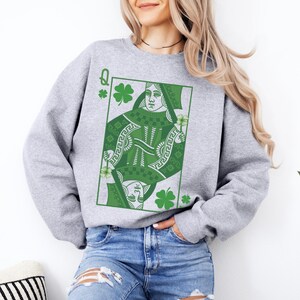 May include: Gray sweatshirt with a green Queen of Hearts playing card graphic. The card features a green shamrock design and the letter Q.