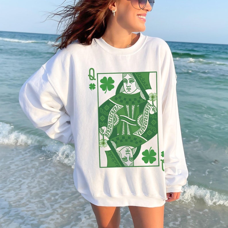 May include: White sweatshirt with a green Queen of Hearts playing card graphic. The card features a green shamrock design and the letter Q.