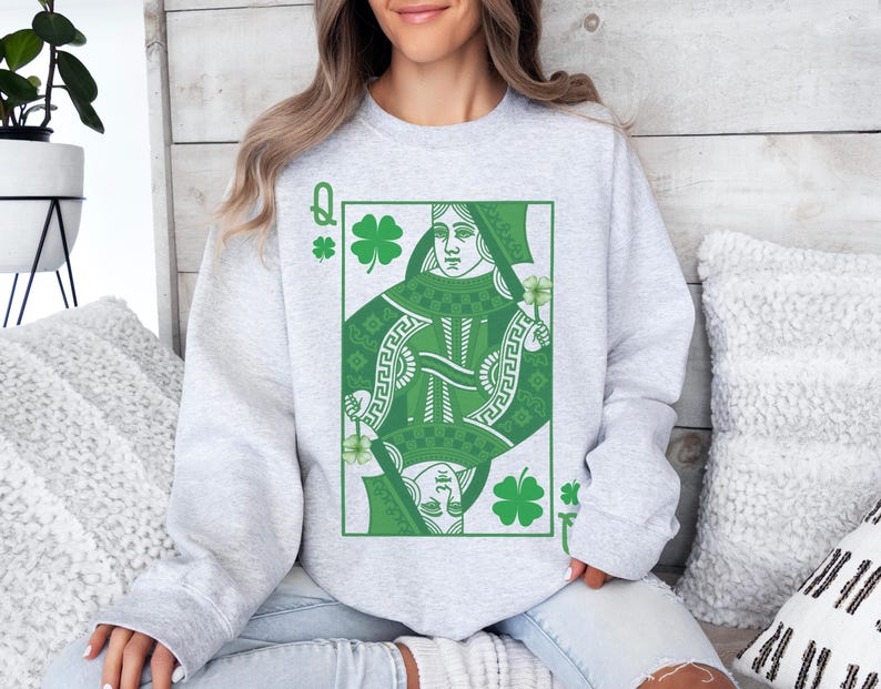 May include: A gray sweatshirt with a green Queen of Clubs playing card design. The card features a green shamrock and a woman with a crown.