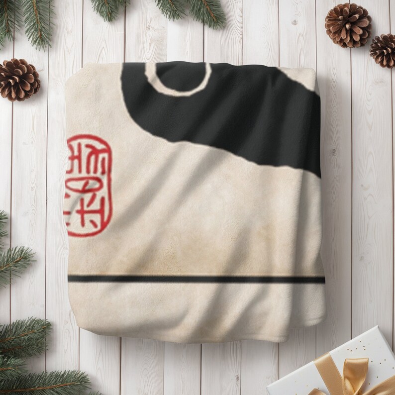 May include: A white throw blanket with a black and white abstract design. The blanket has a red stamp with Chinese characters on it.