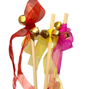 May include: Three wooden sticks with colorful ribbons and bells attached. The ribbons are red, yellow, and pink. The bells are gold.