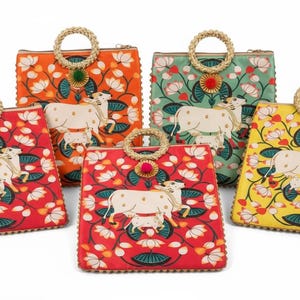 May include: A collection of five square handbags with intricate floral and cow designs. Each bag features a different color: red, orange, green, yellow, and a second red bag. They have woven handles and decorative accents.