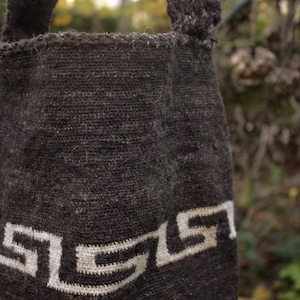 Puede incluir: Una bolsa tejida marr&oacute;n con un dise&ntilde;o geom&eacute;trico blanco. La bolsa tiene dos asas y est&aacute; hecha de una tela gruesa y texturizada.