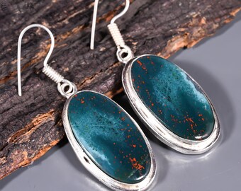 May include: A pair of silver earrings with oval-shaped green and red gemstone stones.