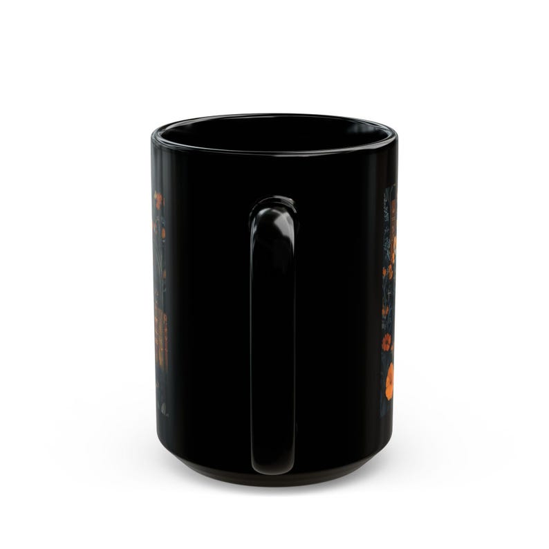 A black ceramic mug with a handle and a floral design on the side.