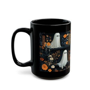 A black mug with a Halloween-themed design featuring a ghost surrounded by flowers and leaves.