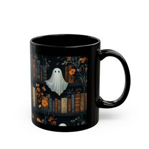 A black mug with a Halloween-themed design featuring a ghost, books, and flowers.