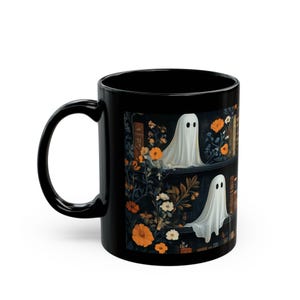 A black mug with a Halloween-themed design featuring a ghost surrounded by flowers and books.