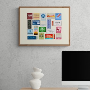 May include: A framed print of a collection of vintage matchboxes with various restaurant and business names, including "Place", "Porterhouse Grill", "Chickens", "The National", "Trapper", "Palma", "Ruby's", "South Kitchen + Bar", and "5&cent;".