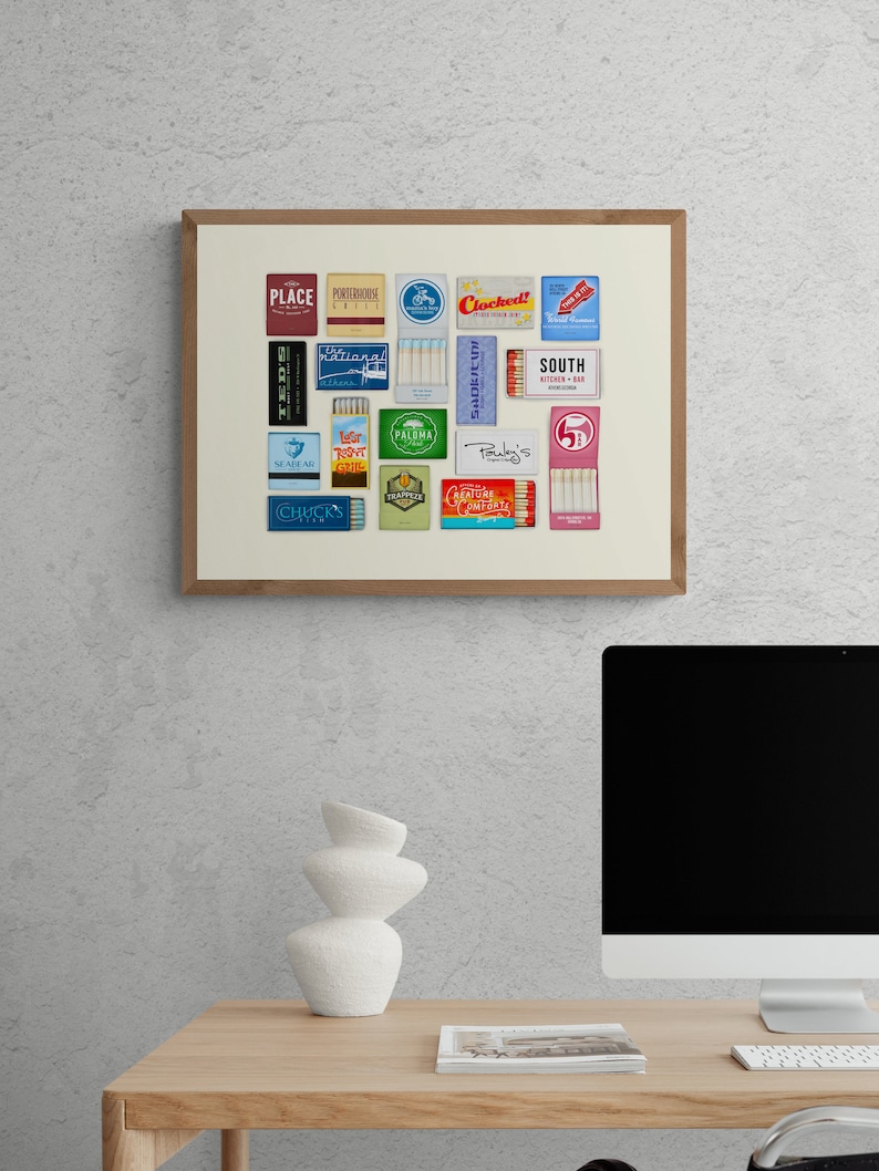 May include: A framed print of a collection of vintage matchboxes with various restaurant and business names, including "Place", "Porterhouse Grill", "Chickens", "The National", "Trapper", "Palma", "Ruby's", "South Kitchen + Bar", and "5&cent;".