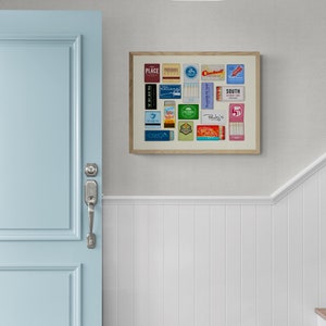 May include: A framed collage of vintage matchbox labels, featuring a variety of designs and colors. The labels are arranged in a grid pattern and include brands like "Place", "Cardinal", and "South".