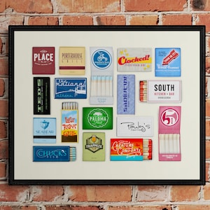 May include: A framed collage of matchbox labels featuring various restaurants and businesses. The labels are in a variety of colors and designs, including red, blue, green, and yellow. Some of the labels feature text, such as "The National", "Seabear", "Clocked!", and "South Kitchen + Bar".