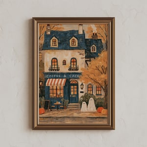 May include: A framed painting of a two-storey building with a blue roof and cream walls, labelled COFFEE & CAKE. The scene features a red and white striped awning, orange autumn trees, two white ghost figures, and pumpkins on the pavement.