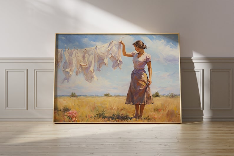 May include: A painting depicting a woman standing in a field, with a line of white laundry hanging on a clothesline behind her. The woman is wearing a pale pink dress and has her hair tied back. The sky is blue with white clouds. The field is a golden yellow colour.