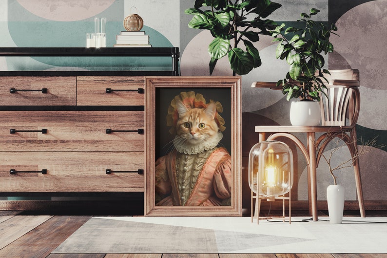 K&ouml;nnte beinhalten: Ein gerahmtes Portr&auml;t einer rotbraunen Katze, die ein rosa-wei&szlig;es Kleid und ein wei&szlig;es Spitzenkragen tr&auml;gt. Das Portr&auml;t h&auml;ngt an einer Wand in einem Raum mit einer Kommode aus Holz und einem Stuhl.