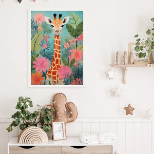 Op de afbeelding: Een ingelijste illustratie van een giraffe met een lichtbruine en oranje gepatenteerde vacht die in een jungle-omgeving staat met roze en groene bloemen. De giraffe kijkt recht naar de kijker.