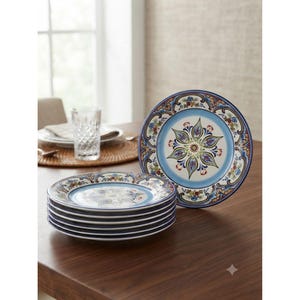 May include: A stack of six round ceramic plates featuring a central floral medallion in shades of blue, green, and red, surrounded by a light blue band and a decorative border with intricate scrollwork and small colorful floral motifs.