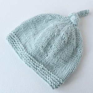 May include: A light blue knitted baby hat with a knotted top.