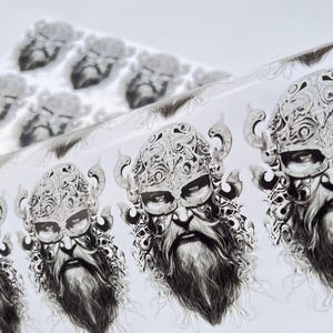 Puede incluir: Ilustración en blanco y negro de la cara de un guerrero vikingo, con un casco detallado y barba. La imagen se repite sobre una superficie blanca, creando un patrón. La obra de arte tiene una apariencia detallada y dibujada a mano.
