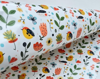 Può includere: Carta da regalo bianca con un motivo ripetuto di uccelli, fiori e foglie colorate. Gli uccelli sono gialli, arancioni e neri, mentre i fiori sono blu, arancioni e gialli. Foglie e steli verdi completano il design.